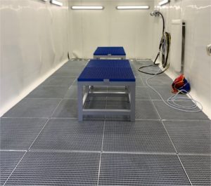 Die neue Strahlkabine im Einsatz mit Werkstücken auf einem Podest