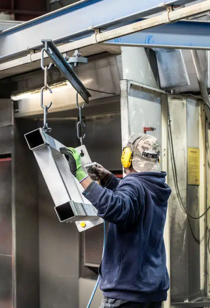 Mitarbeiter von KBN mit großem Werkstück bei der Vorbereitung zur Pulverbeschichtung