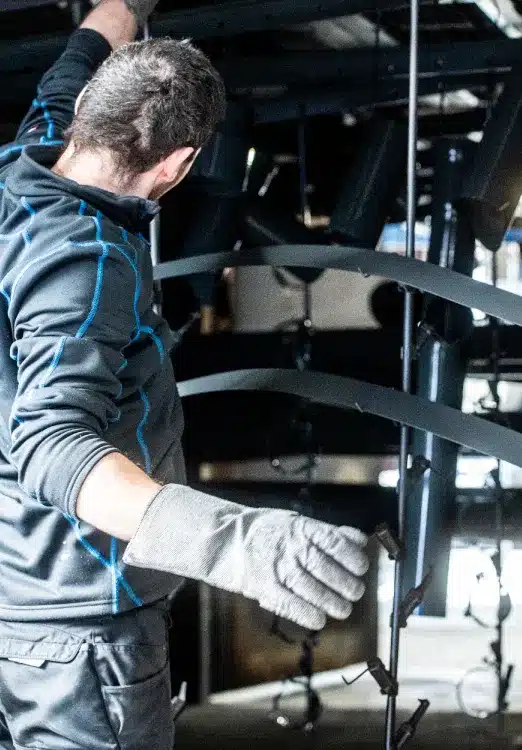 Erfahrener Mitarbeiter bei Pulverbeschichtung von Werkstücken