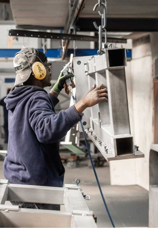 Mitarbeiter von KBN mit großem Werkstück bei der Pulverbeschichtung